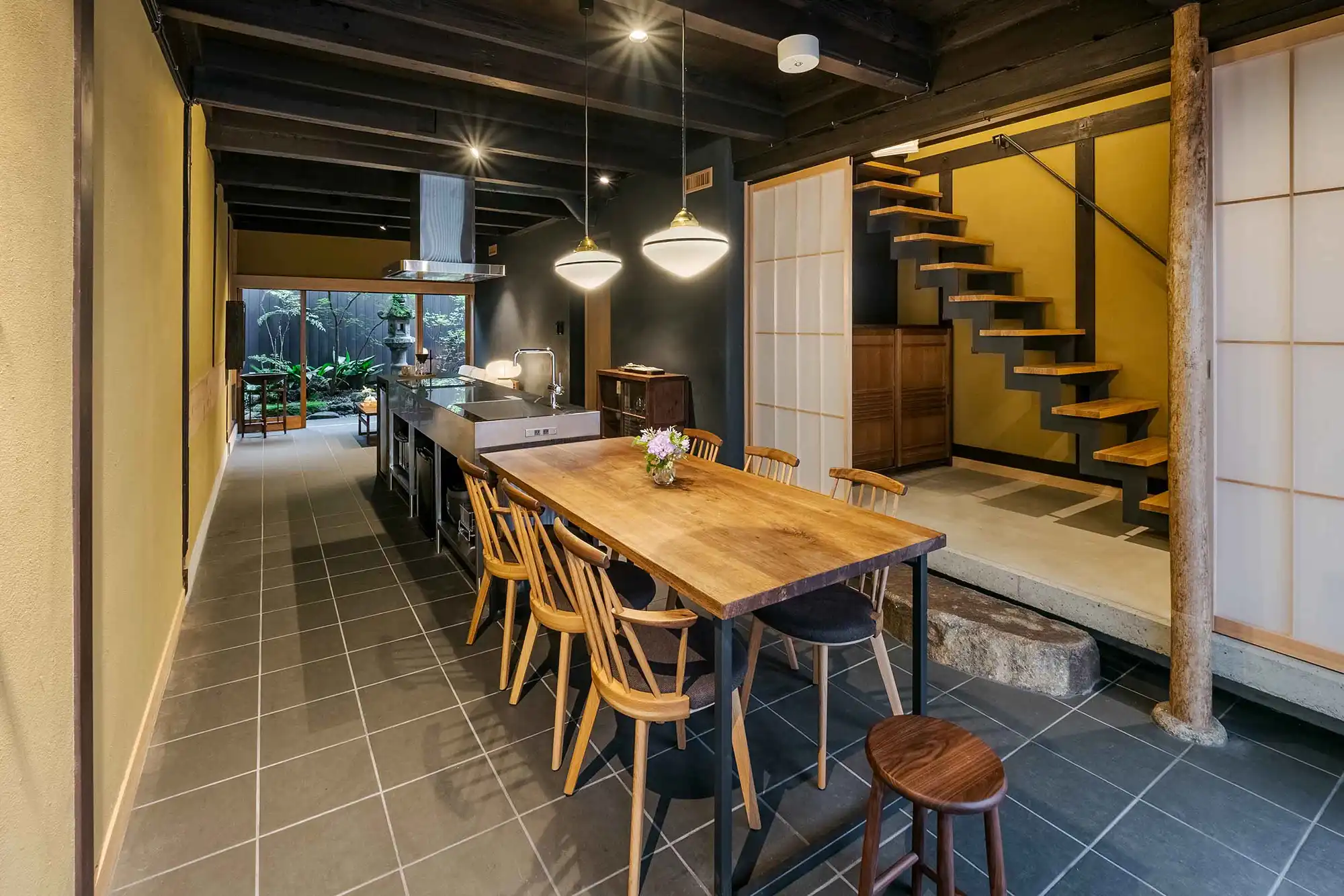 Interior of a traditional Japanese house in Kyoto, featuring a wooden dining table, Japanese garden, and soft ambient lighting.